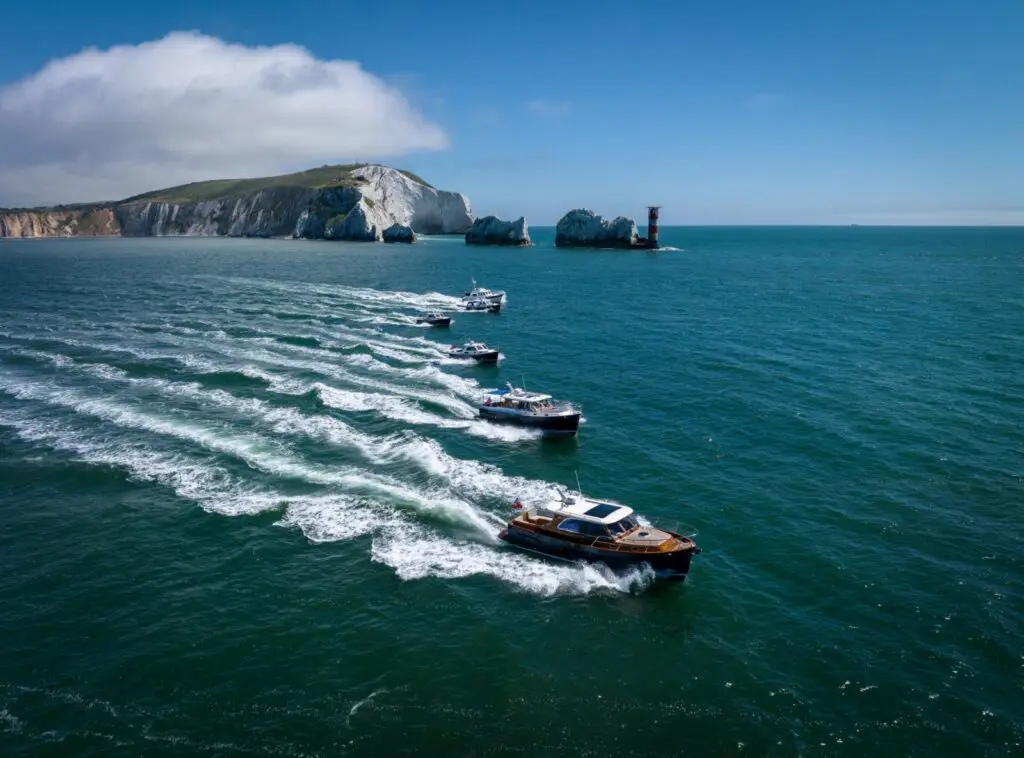 Line of Duchy motor launches led by a dark-hulled Duchy 35 passing the Needles off the Isle of Wight