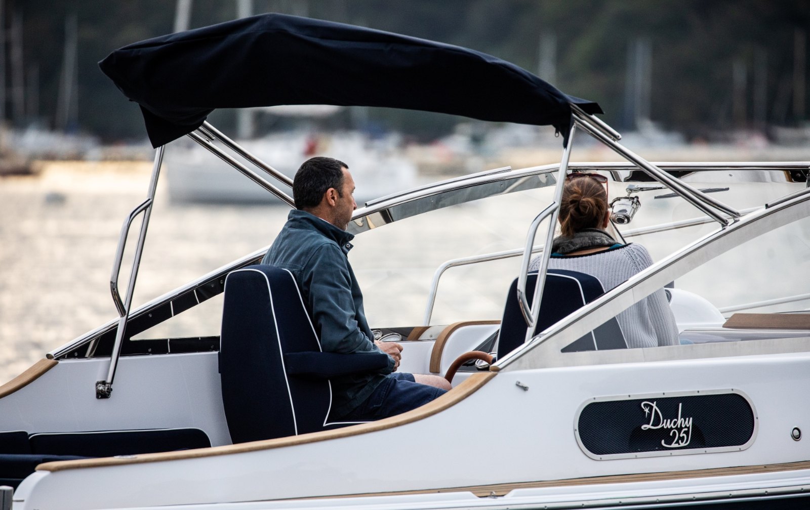 At the helm of the Cockwells Duchy 25 under its canopy, with guests seated in the cockpit