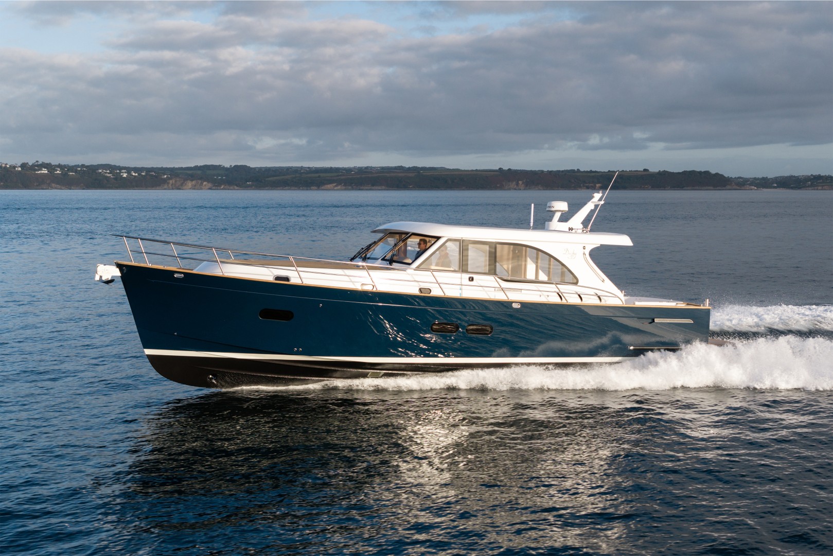 Duchy 45 motor launch running at speed, side profile with navy hull and varnished transom