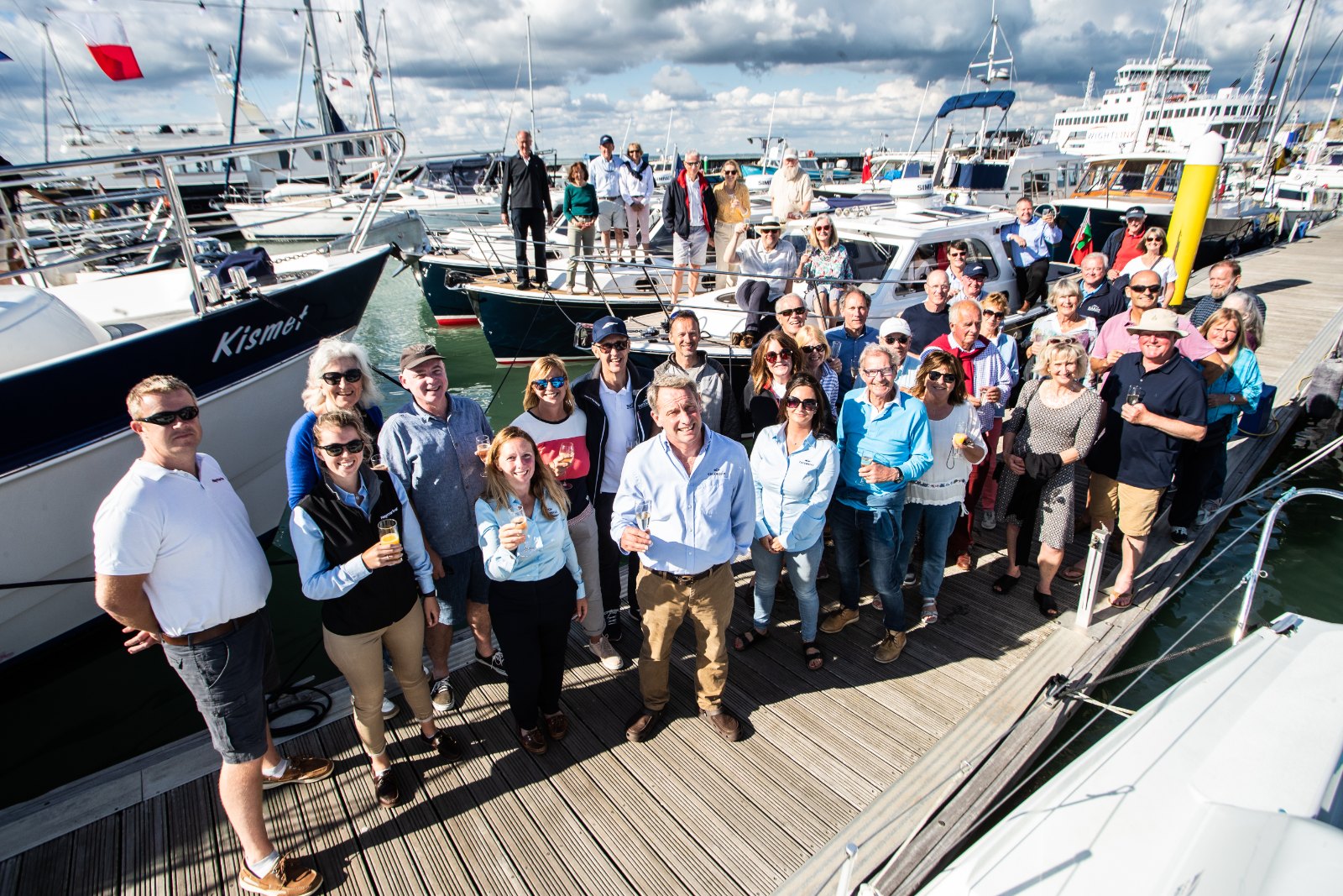 Owners and guests of the Cockwells Owners' Rally 2022 gathered for a group photo on the pontoon at Yarmouth Harbour