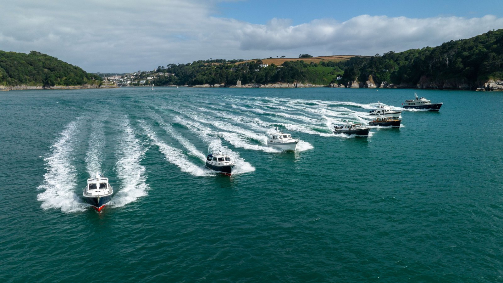 Six Cockwells boats from the 2023 Owners' Rally fleet under way in formation, photographed from a drone