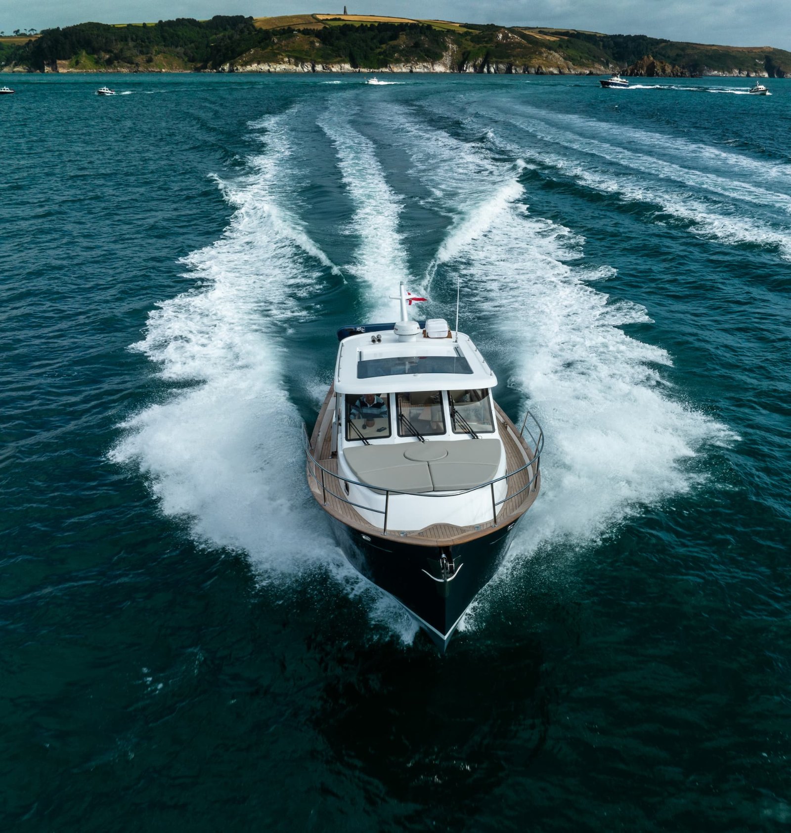 Duchy 35 with sunroof open seen from behind by drone, following other boats across a bay