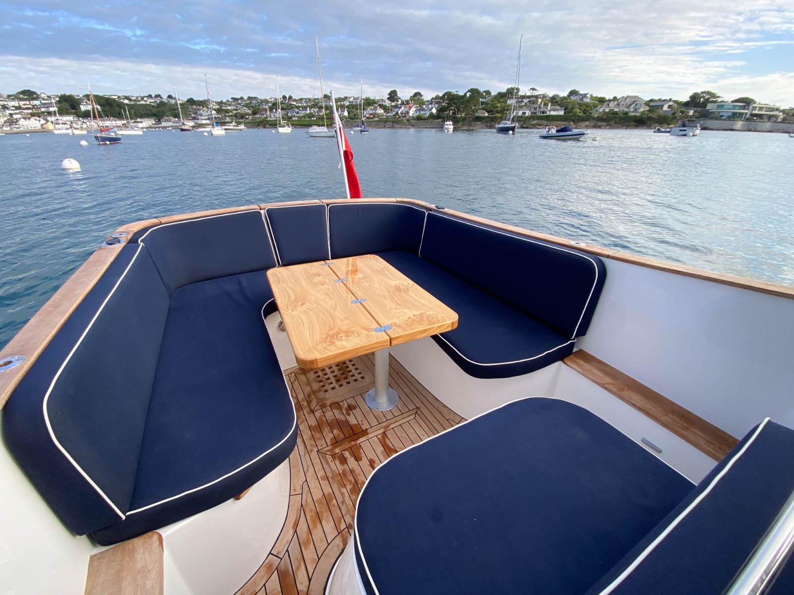 Cockpit of the Duchy 27 'Zena' at a mooring, with navy upholstery and a teak table