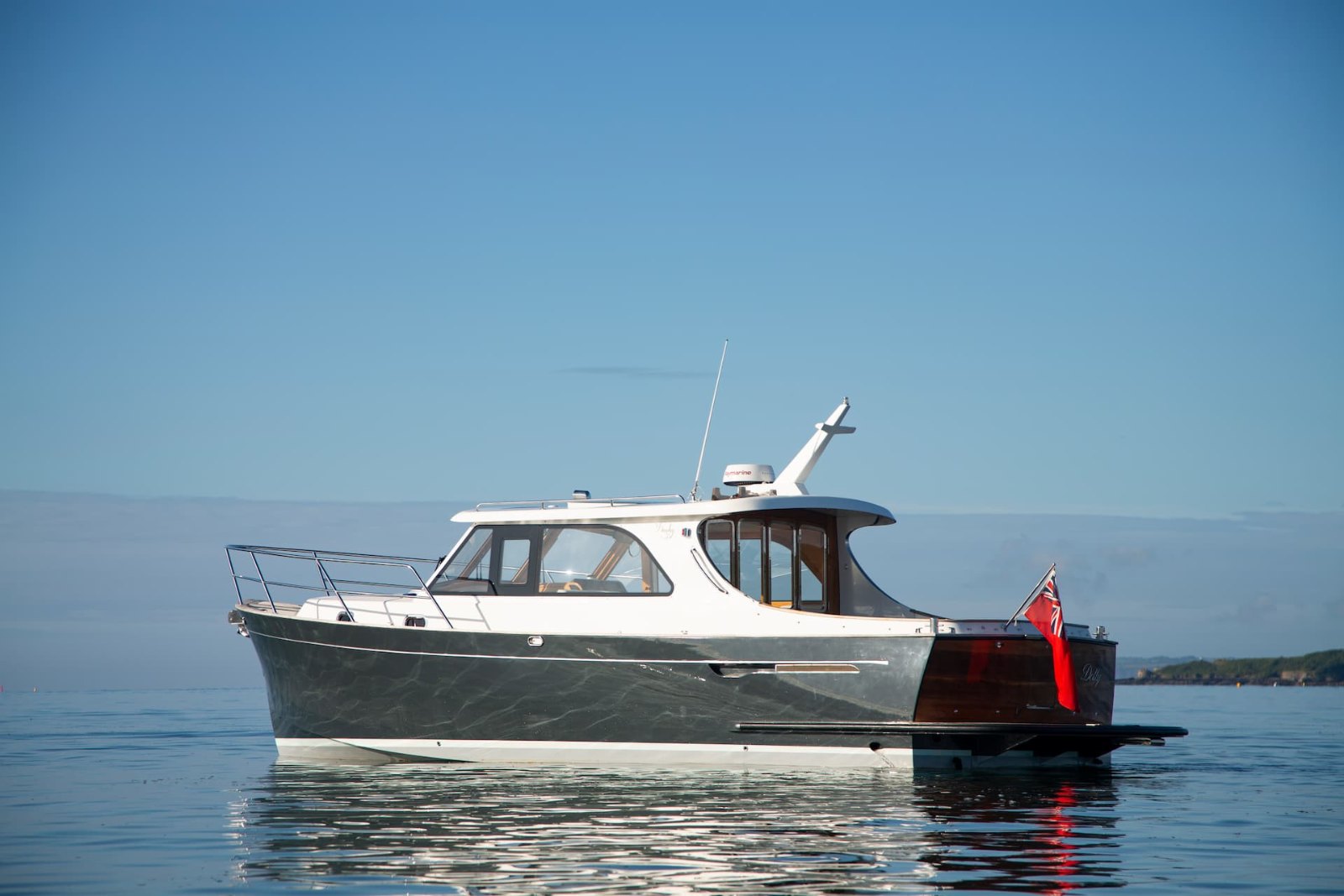Duchy 35 'Dolly' with grey hull and varnished teak transom lying on flat water