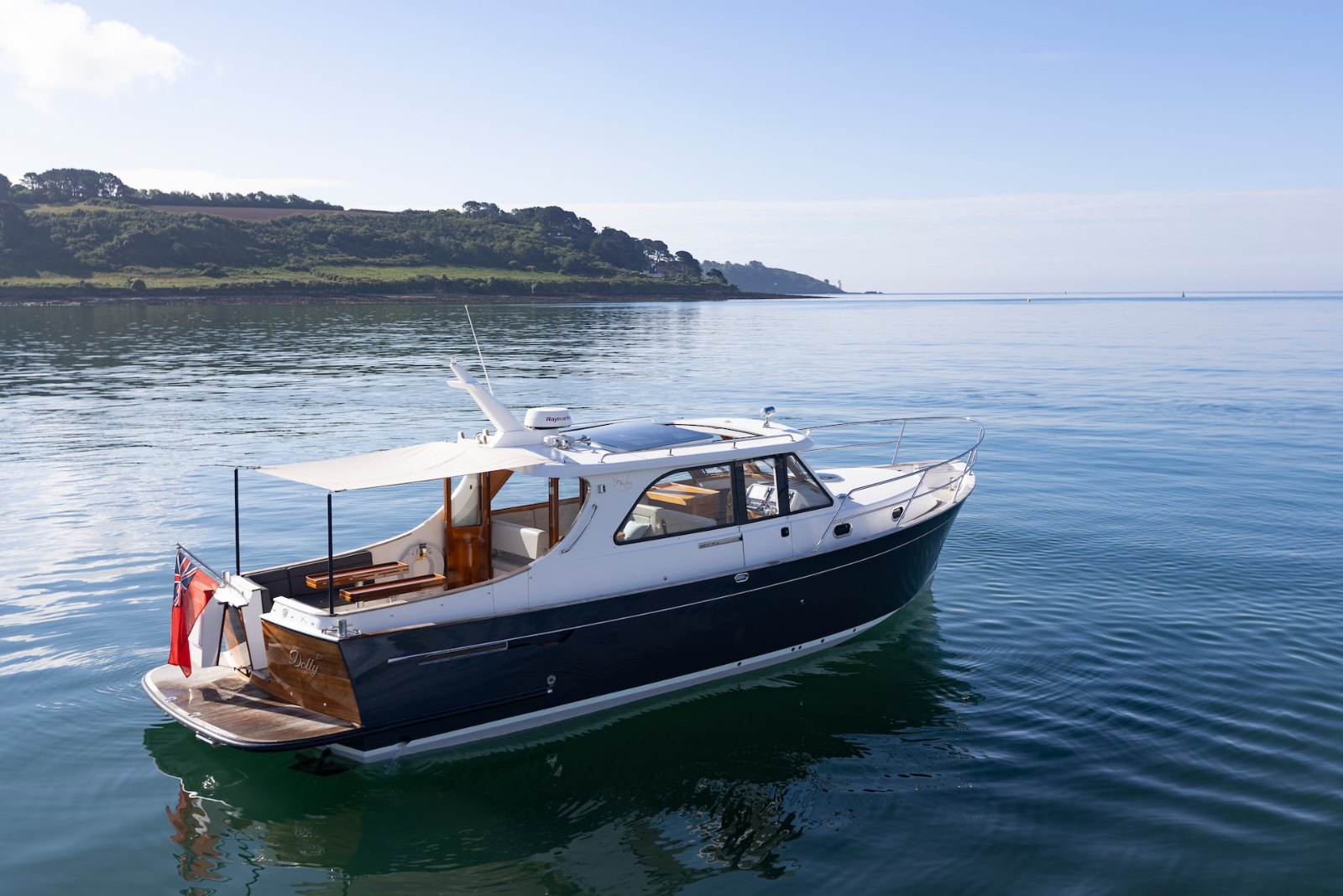Stern-quarter view of the Duchy 35 'Dolly' off a headland, showing her teak transom